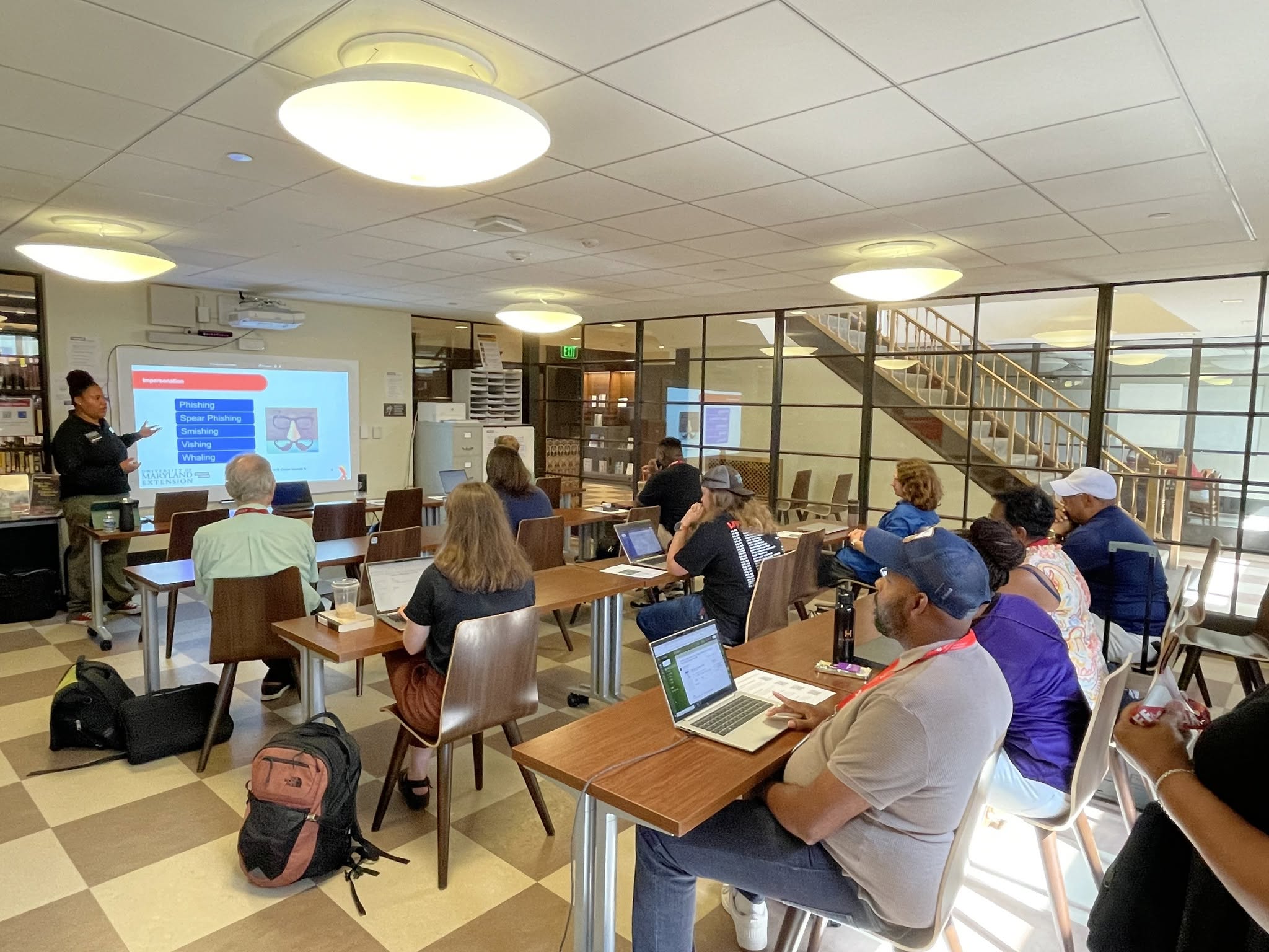 UME Marylanders Online Tech Educator Naimani Staley standing in front of a classroom next to a screen teaching a digital skills class in Baltimore.